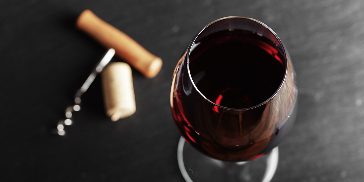 wine glass of red wine with a corkscrew.