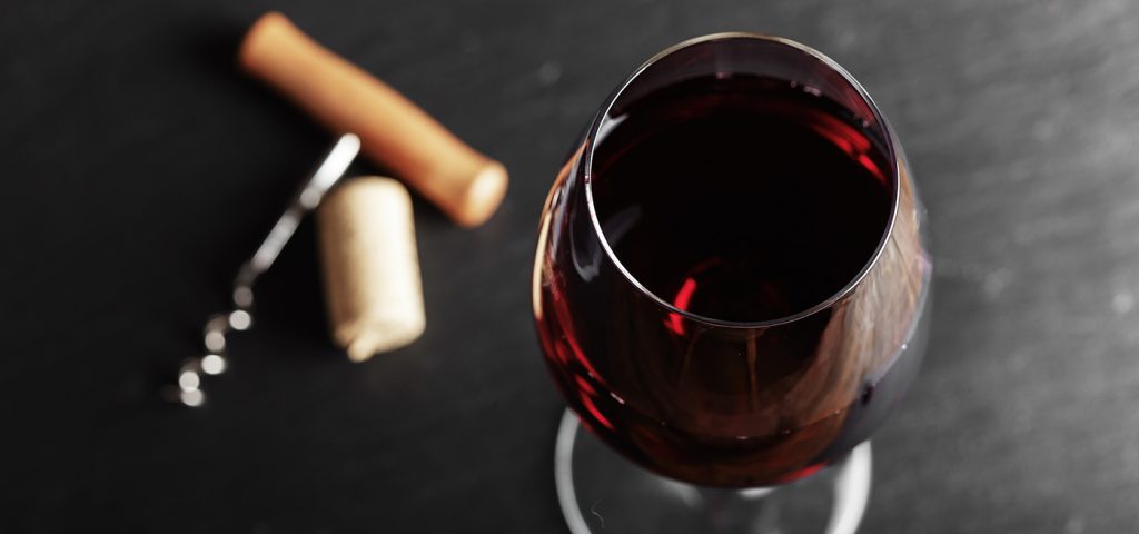 wine glass of red wine with a corkscrew.